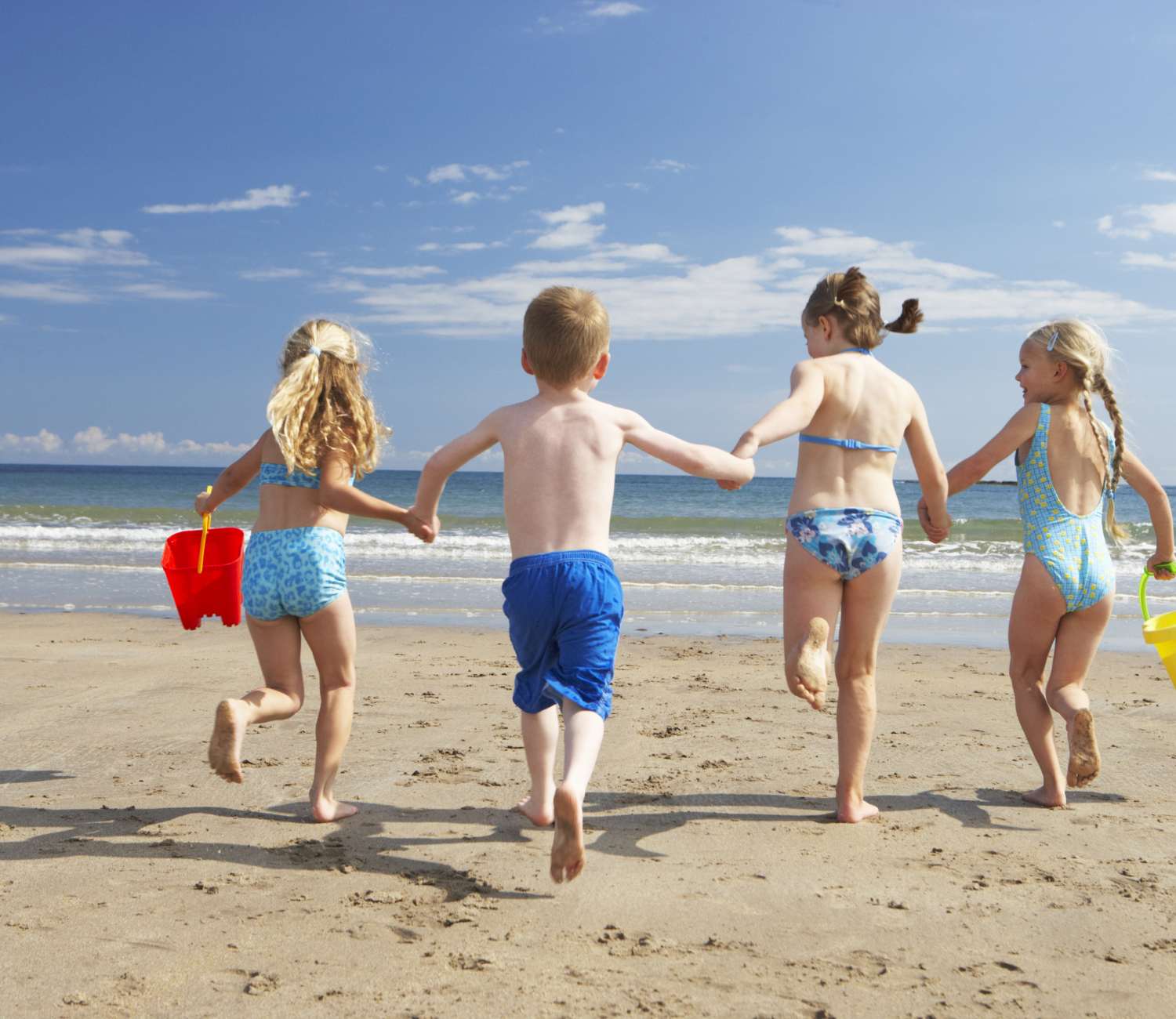 ילדים בחופשה בחול רצים על חוף הים